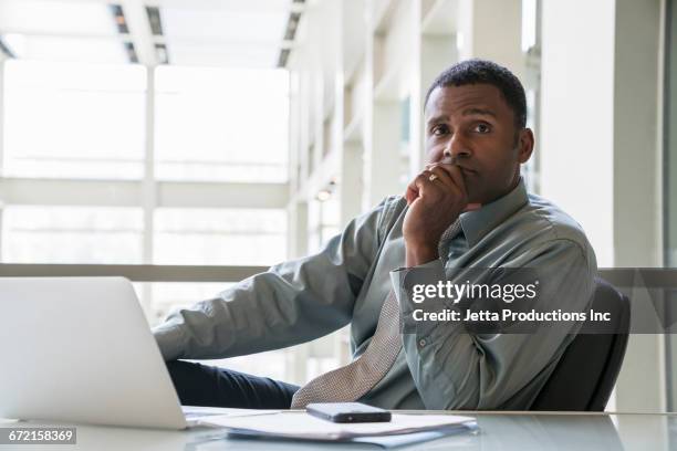 pensive black businessman sitting at desk - good technology inc stock pictures, royalty-free photos & images