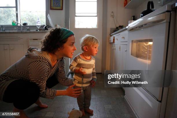 mother and son looking in oven window - real people family stock pictures, royalty-free photos & images
