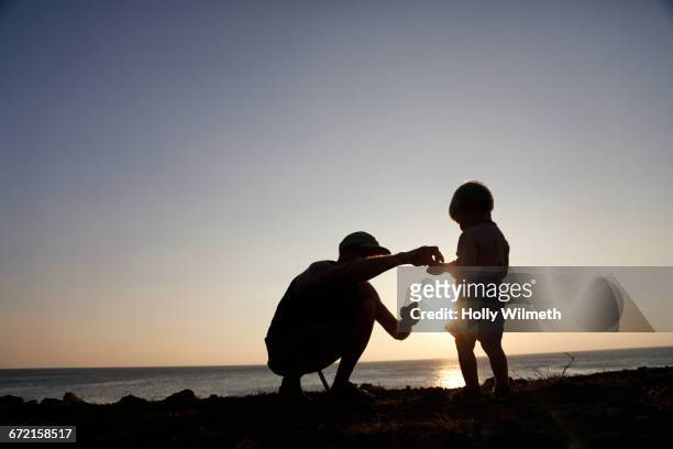 silhouette of father and son exploring at beach - grandfather silhouette stockfoto's en -beelden