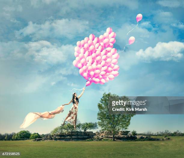 chinese woman being lifted in field by bouquet of pink balloons - helium stock-fotos und bilder