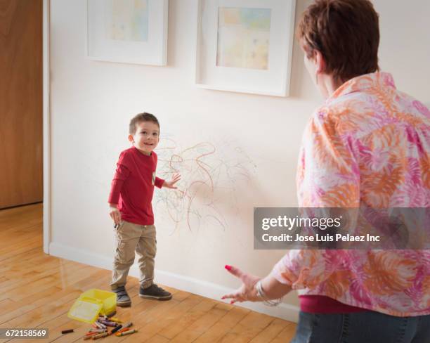 grandmother angry at grandson drawing on wall with crayons - irreverent stock-fotos und bilder