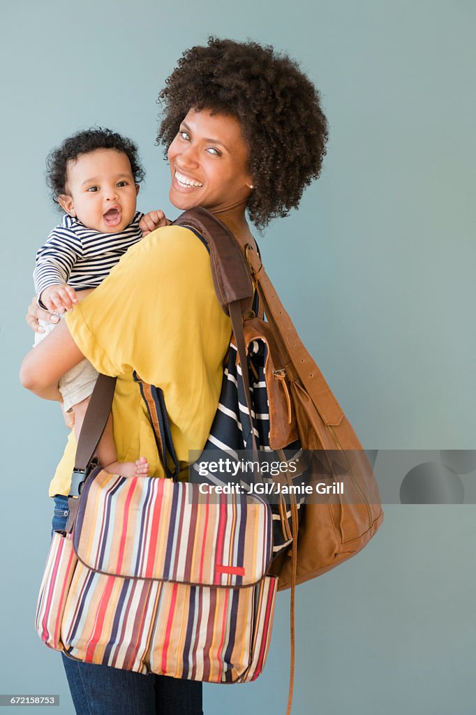 Mother carrying three bags and baby son