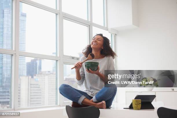 mixed race woman eating chocolate from bowl with wooden spoon - convenience chocolate stock pictures, royalty-free photos & images