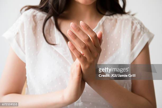 hispanic woman rubbing hands - hand rubbing stockfoto's en -beelden