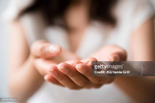 hispanic woman cupping hands - offering ストックフォトと画像