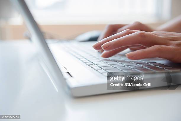 hands of hispanic woman typing on laptop - teclado de computador fotografías e imágenes de stock