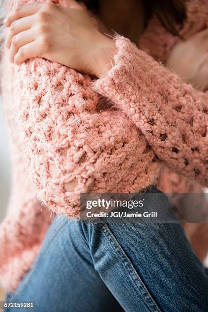 hispanic woman wearing pink sweater and jeans - hugging mid section stock pictures, royalty-free photos & images