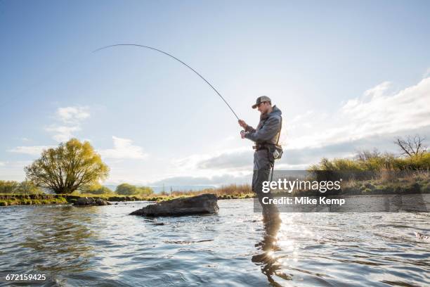caucasian man fly fishing in river - fishing reel stock pictures, royalty-free photos & images