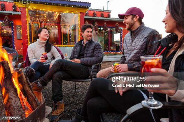 couples drinking cocktails and beer outdoors at storefront campfire - taos stock-fotos und bilder