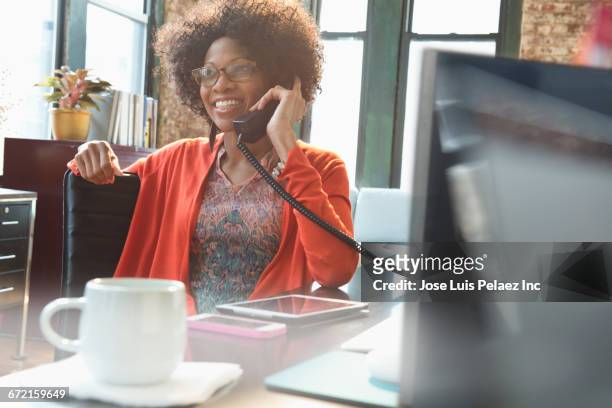 black businesswoman talking on telephone at desk - festnetztelefon stock-fotos und bilder