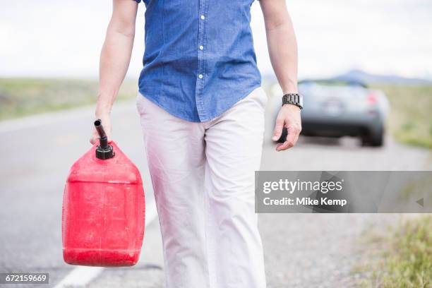 caucasian man carrying gas on street - jerrican photos et images de collection