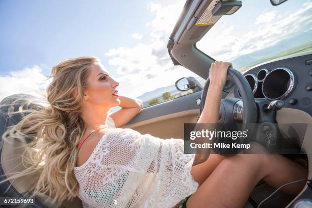 caucasian woman driving in sports car - junge frau allein stock-fotos und bilder