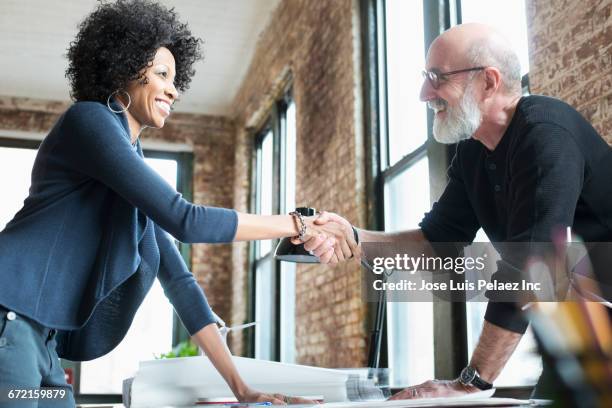 business people handshaking over blueprints on desk - plan architecte photos et images de collection