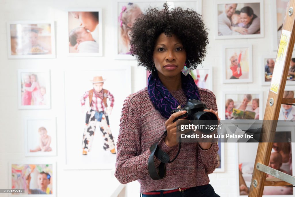 Black photographer holding camera in studio