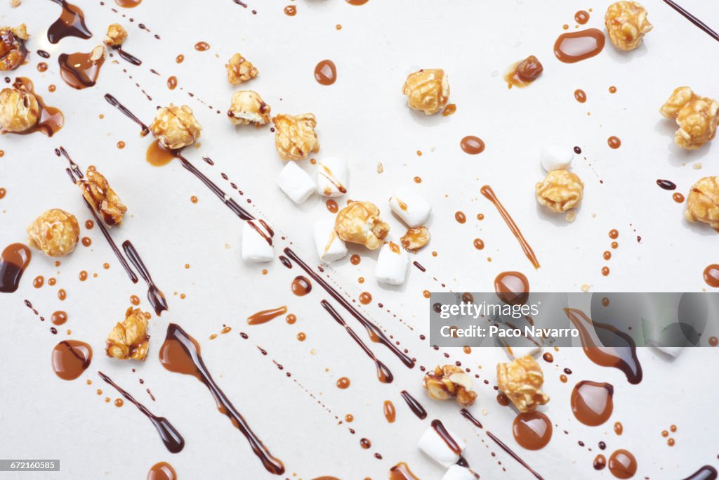 Chocolate, caramel popcorn and marshmallows on white background