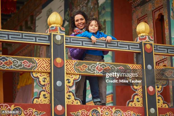 mixed race mother holding son on balcony - thimphu stock pictures, royalty-free photos & images