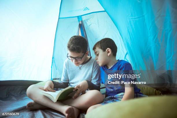 hispanic boys camping in tent and reading book - zapopan stock pictures, royalty-free photos & images