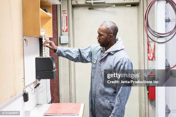 worker selecting time card in factory - work-time-clock stock pictures, royalty-free photos & images