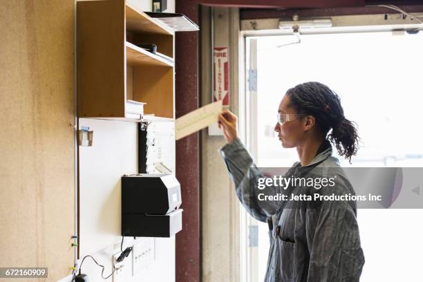 mixed race worker selecting time card in factory - time clock stock pictures, royalty-free photos & images