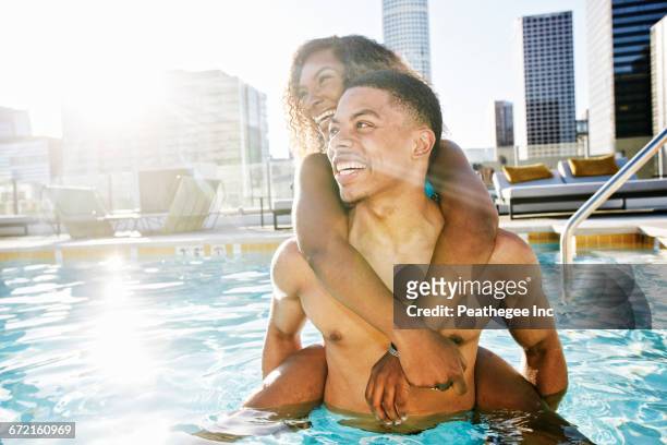 smiling couple enjoying urban swimming pool - rooftop pool imagens e fotografias de stock