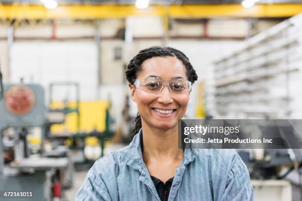 smiling mixed race worker in factory - industrial portraits character photos et images de collection