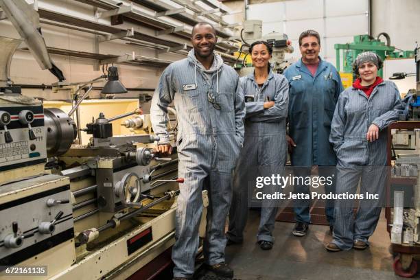 smiling workers posing in factory - industrial laborer foto e immagini stock