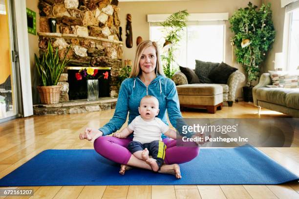 Mother meditating on exercise mat with baby in lap