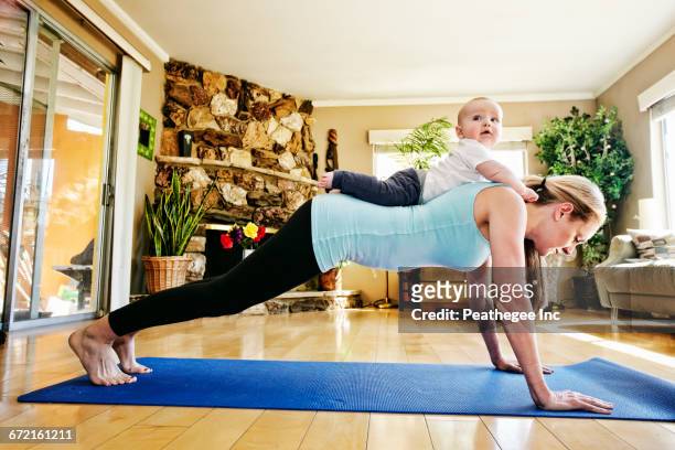 mother working out on exercise mat with baby on back - multitasking mum stock pictures, royalty-free photos & images