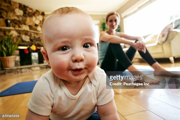 baby crawling on floor while mother rests from workout - crawling stock pictures, royalty-free photos & images