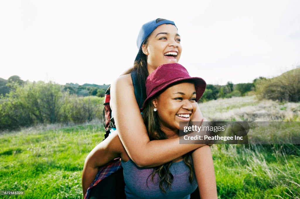 Mixed Riding Mixed Race Teenager Giving Sister Piggyback Ride In Field High-Res ...