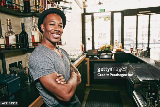 smiling black bartender relaxing behind bar - barman stock pictures, royalty-free photos & images
