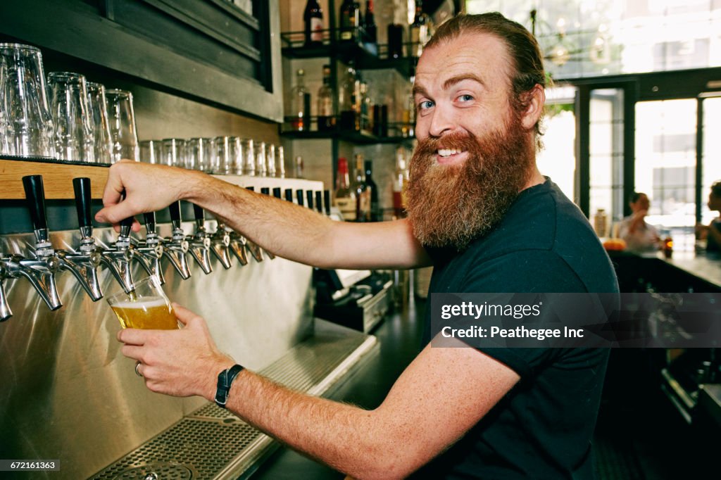 Smiling Caucasian bartender pouring beer