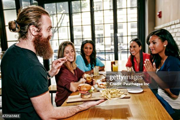 waiter serving foods to friends at table in bar - gastro pub stock pictures, royalty-free photos & images