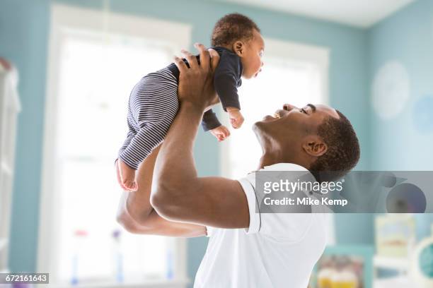 black father lifting baby son - camera dei bambini foto e immagini stock