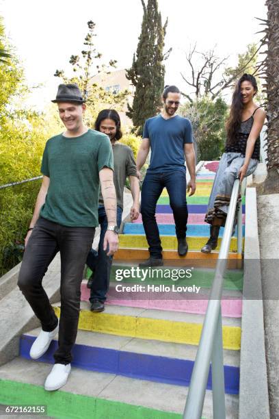 friends descending multicolor staircase - rutsche stock-fotos und bilder