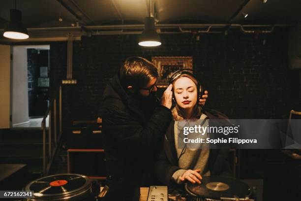 caucasian dj holding headphones on woman - equipo de alta fidelidad fotografías e imágenes de stock