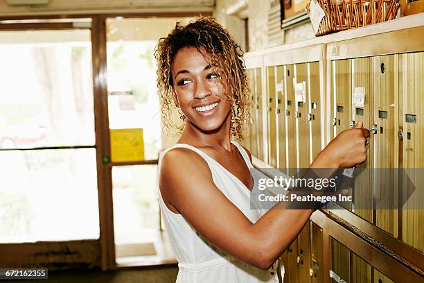 smiling mixed race woman unlocking apartment mailbox - the apartment by the line la opening stock pictures, royalty-free photos & images