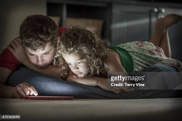 caucasian brother and sister laying on floor using cell phone - houston texas family stock pictures, royalty-free photos & images