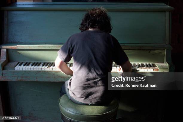 caucasian boy playing worn green piano - piano stock pictures, royalty-free photos & images