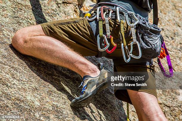 carabiners on caucasian man climbing rock - safety harness stock pictures, royalty-free photos & images