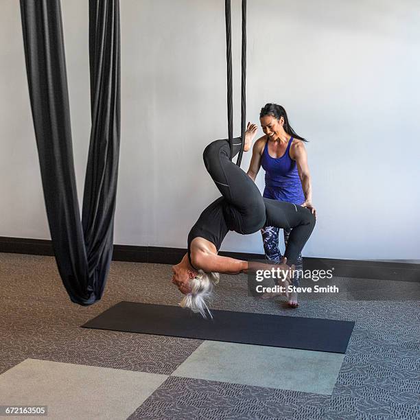 instructor assisting student hanging from silks - al revés posición descriptiva fotografías e imágenes de stock