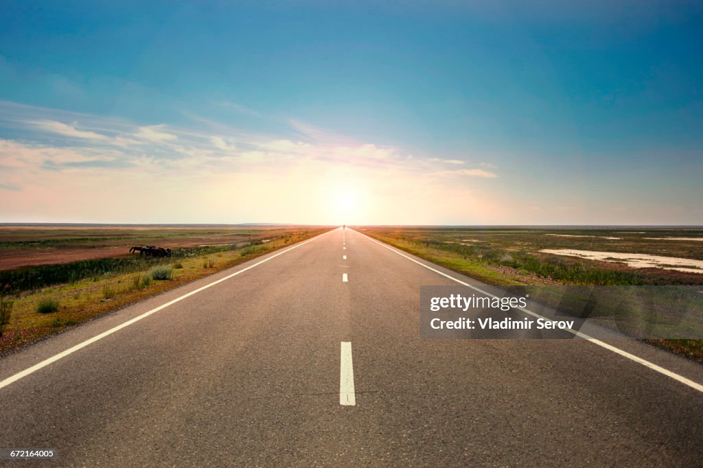 Sunset over distant empty highway
