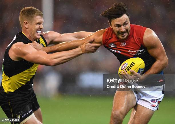 Michael Hibberd of the Demons fends off atackle by Josh Caddy of the Tigers during the round five AFL match between the Richmond Tigers and the...