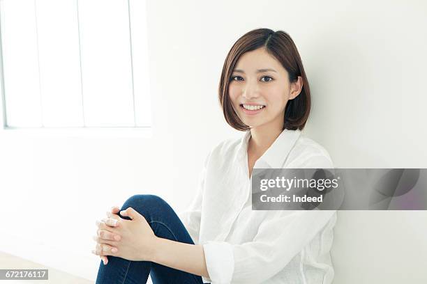 young woman sitting on floor - woman holding legs fotografías e imágenes de stock