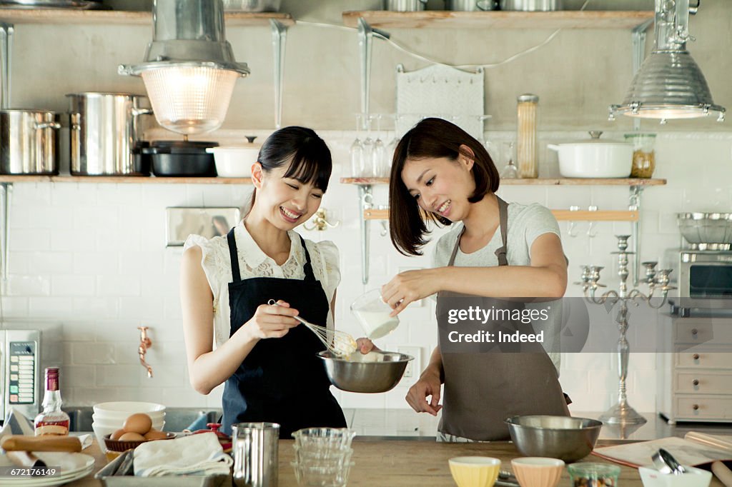 Young women cooking together in kitchen