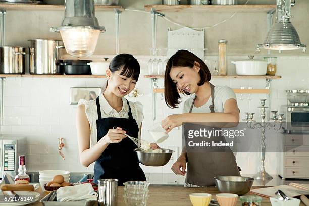 young women cooking together in kitchen - cooking apron stock pictures, royalty-free photos & images