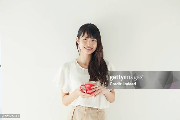 smiling young woman holding coffee cup - cup portraits foto e immagini stock