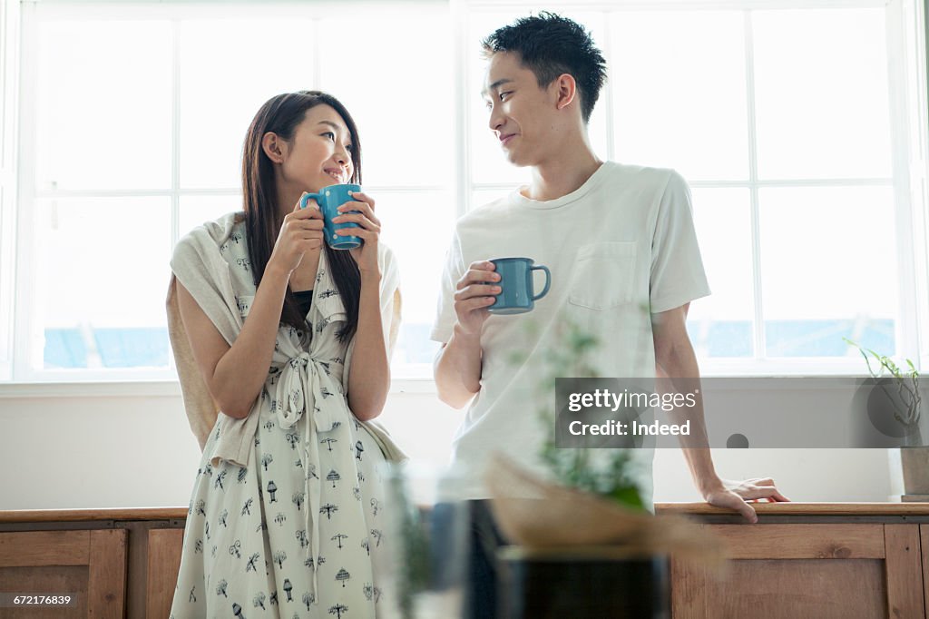 Young couple having coffee by window