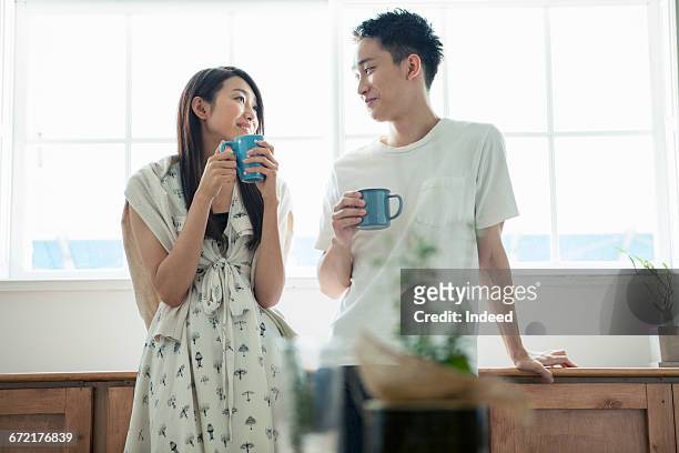 young couple having coffee by window - the japanese wife stock pictures, royalty-free photos & images