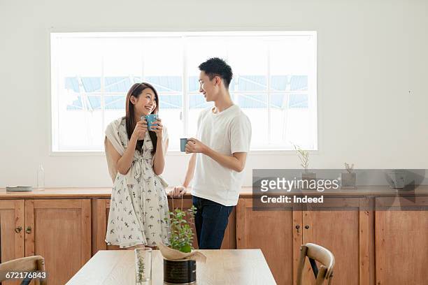 young couple having coffee in dining room - asian young couple stock pictures, royalty-free photos & images